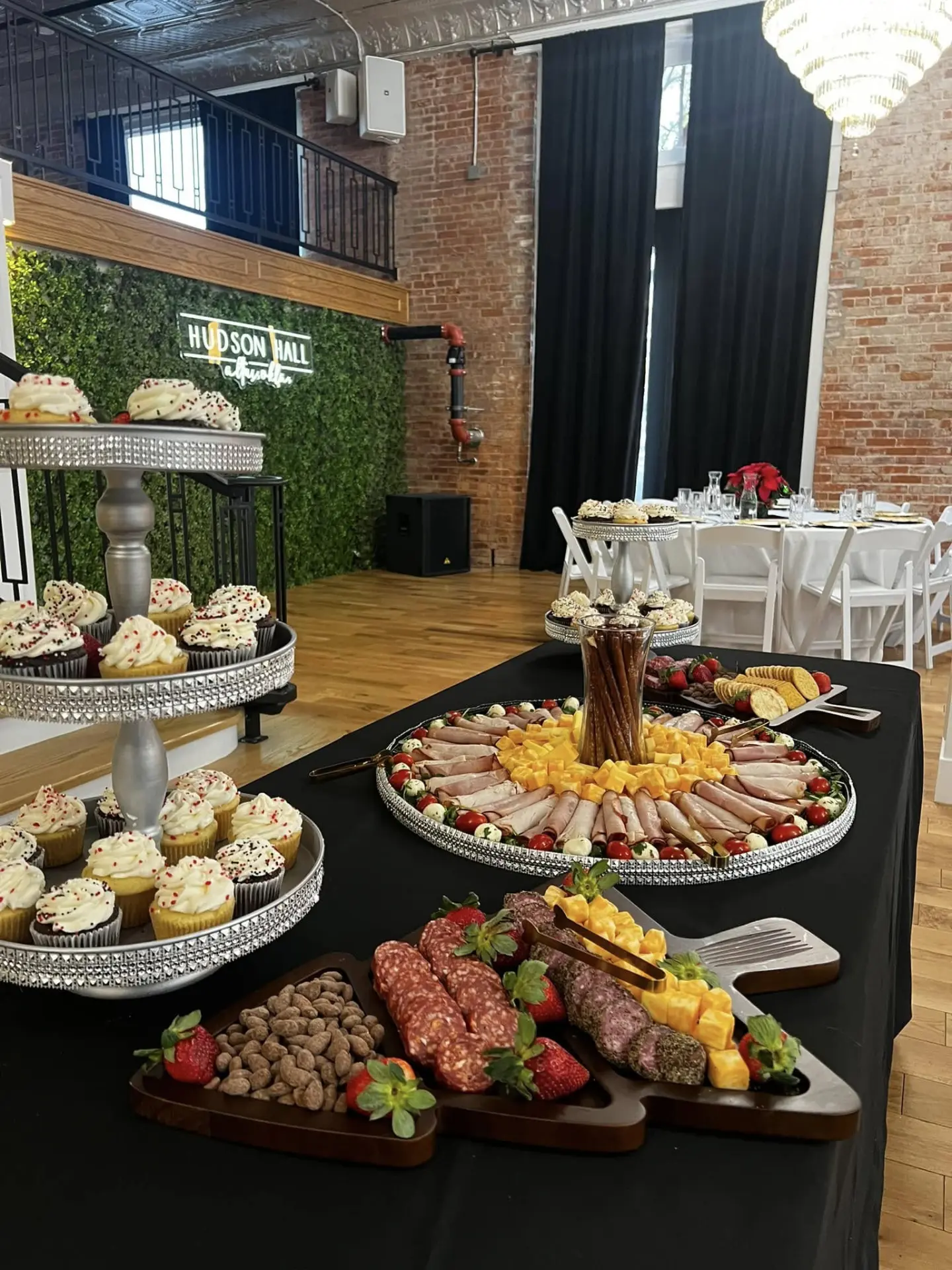 Elegant catering display with charcuterie boards, cupcakes, and appetizers at Hudson Hall
