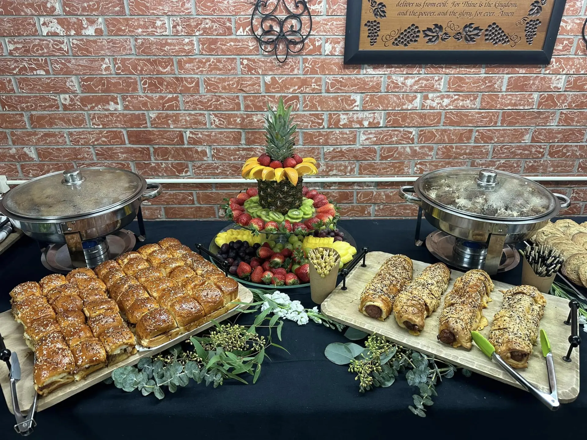 Buffet spread with sliders, fruit tower, and cajun pigs in a blanket